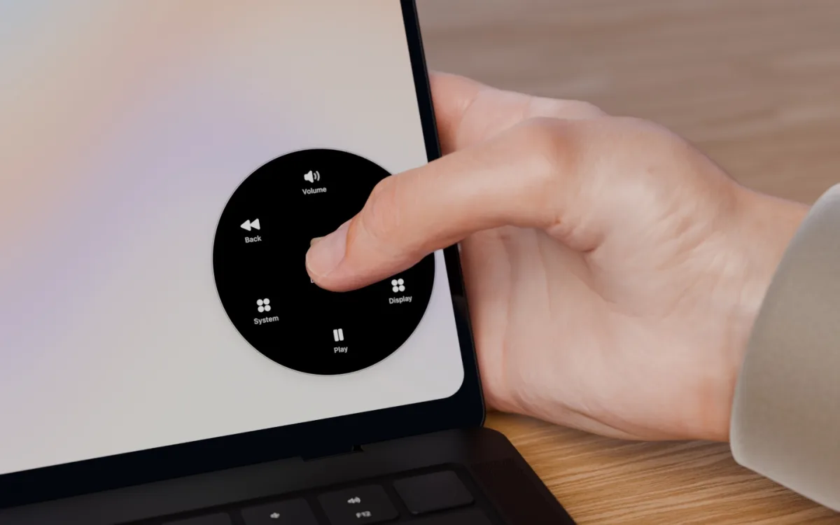 A thumb presses the MacBook's screen near its lower corner and Radial's dial opens under it.